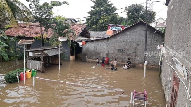 Sejumlah anak sedang asyik berendam banjir di rumah mereka di Kebon Pala Jaktim. (Suara.com/Yaumal)