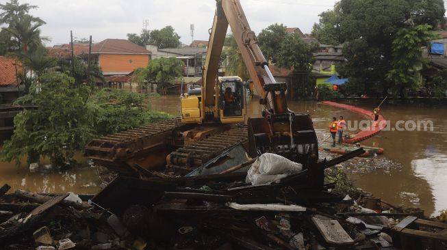 Petugas UPK Badan Air Kecamatan Makasar dibantu alat berat melakukan pengerukan sampah di Kali Sunter, Kelurahan Cipinang Melayu, Jakarta, Jumat (19/2/2021). [Suara.com/Angga Budhiyanto]