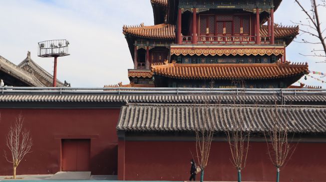 Seorang warga berjalan di samping Kuil Yonghegong yang ditutup untuk umum di Distrik Dongcheng, Kota Beijing, China, Kamis (18/2/2021). ANTARA FOTO/M. Irfan Ilmie
