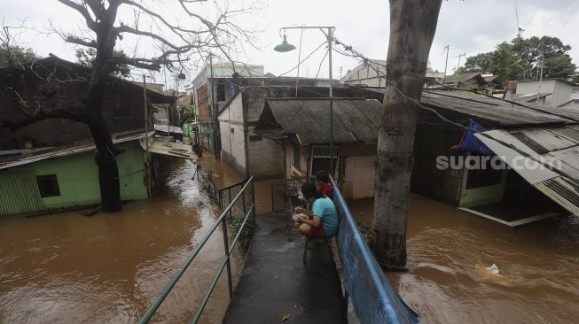 Warga beraktivitas saat banjir merendam Kelurahan Cipinang Muara, Jakarta, Jumat (19/2/2021). [Suara.com/Angga Budhiyanto]