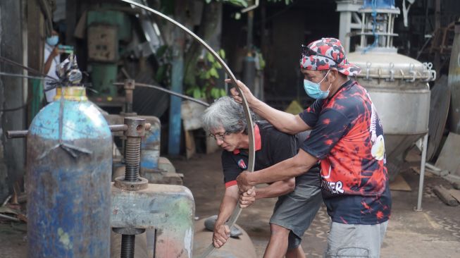 Mantan Wali Kota Solo FX. Hadi Rudyatmo (kanan) membantu pekerja mengelas besi di bengkel las miliknya Pucang Sawit, Solo, Jawa Tengah, Jumat(19/2/2021). ANTARA FOTO/Mohammad Ayudha