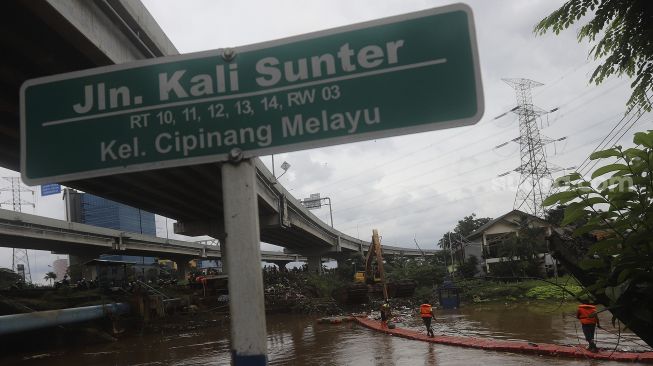 Petugas UPK Badan Air Kecamatan Makasar dibantu alat berat melakukan pengerukan sampah di Kali Sunter, Kelurahan Cipinang Melayu, Jakarta, Jumat (19/2/2021). [Suara.com/Angga Budhiyanto]