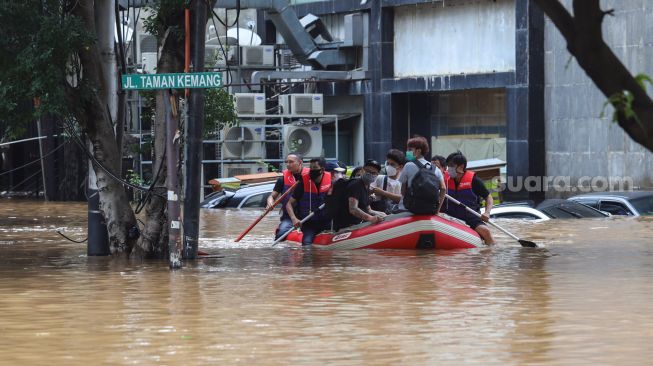 Warga mengungsi dari banjir dengan menggunakan perahu karet di Kemang, Jakarta Selatan, Sabtu (20/2/2021). [Suara.com/Alfian Winanto]