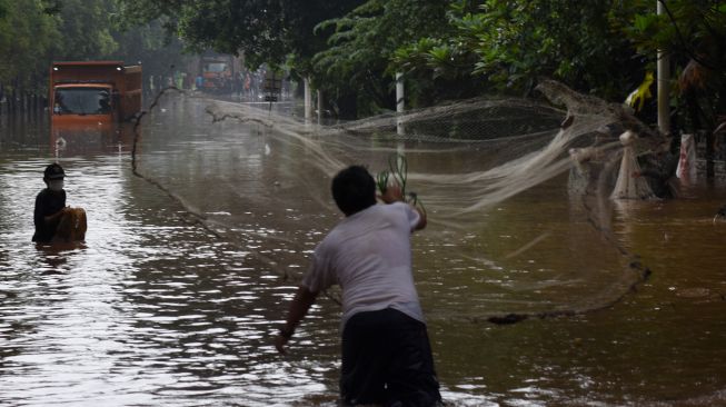 Warga menjala ikan di ruas Tol TB Simatupang, Jakarta Selatan, Sabtu (20/2/2021).  ANTARA FOTO/Indrianto Eko Suwarso