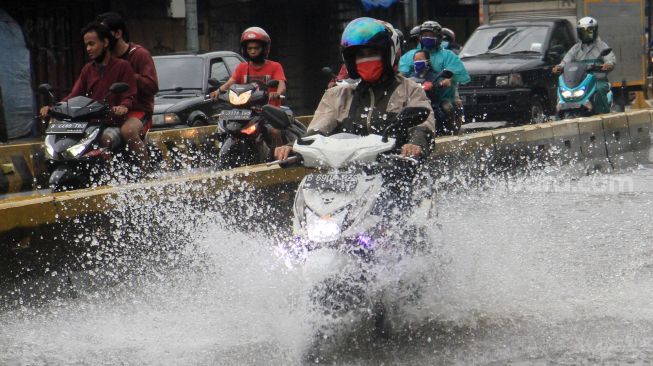 Pengendara melintas  di Jalan Jatinegara Barat, Jakarta Timur yang tersendat akibat sebagian badan jalan terendam banjir luapan Sungai Ciliwung dengan ketinggian sekitar 20 sentimeter, Sabtu (20/2). [Suara.com/Oke Atmaja]
