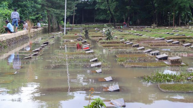 Penampakan area makam yang terendam banjir di TPU Jeruk Purut, Jakarta Selatan, Sabtu (20/2/2021). [Suara.com/Alfian Winanto]