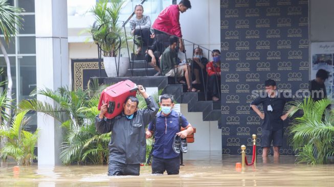 Warga mengungsikan barang - barangnya dari banjir di Kemang, Jakarta Selatan, Sabtu (20/2/2021). [Suara.com/Alfian Winanto]