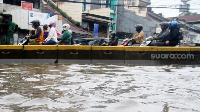 Suasana arus lalu lintas di Jalan Jatinegara Barat, Jakarta Timur yang tersendat akibat sebagian badan jalan terendam banjir luapan Sungai Ciliwung dengan ketinggian sekitar 20 sentimeter, Sabtu (20/2). [Suara.com/Oke Atmaja]
