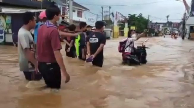 Seorang Ibu nekat dorong motor terjang banjir di depan Perumahan Nasio, Jatiasih, Kota Bekasi, Sabtu (20/2/201).[Instagram/@net2netnews]