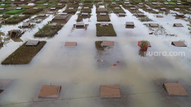 Kondisi puluhan makam yang terendam banjir di TPU Jeruk Purut, Jakarta Selatan, Sabtu (20/2/2021). [Suara.com/Alfian Winanto]