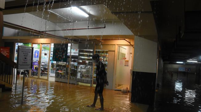 Pengunjung melintas di depan toko yang terendam banjir di salah satu pusat perbelanjaan Kem Chicks kawasan Kemang, Jakarta Selatan, Sabtu (20/2/2021). ANTARA FOTO/Indrianto Eko Suwarso
