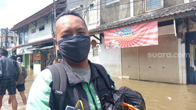 Wendi Handoyono pengemudi ojol antarkan makanan di tengah kepungan banjir di Ciledug Indah, Karang Tengah, Kota Tangerang, Minggu (21/2/2021). [Suara.com/Muhammad Jehan Nurhakim]