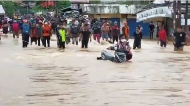 Ibu-ibu dorong motor terjang banjir di Jalan Jatimekar, Jatiasih, Kota Bekasi. 