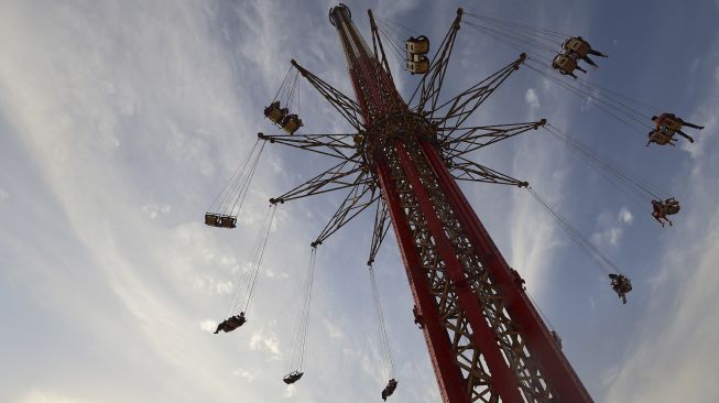 Pengunjung menaiki wahana 'sky flyer' di Taman Bollywood, Dubai, pada (18/2/2021). [GIUSEPPE CACACE / AFP]