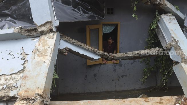 Warga mengamati puing-puing reruntuhan di rumahnya yang tertimpa tanah longsor di Kelurahan Bangka, Mampang Prapatan, Jakarta, Minggu (21/2/2021). [Suara.com/Angga Budhiyanto]