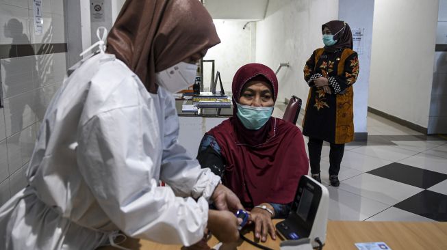 Petugas kesehatan memeriksa kadar oksigen pada tubuh warga lanjut usia (lansia) di RSUD Tanjung Priok, Jakarta Utara, Sabtu (20/2/2021). [ANTARA FOTO/M Risyal Hidayat]