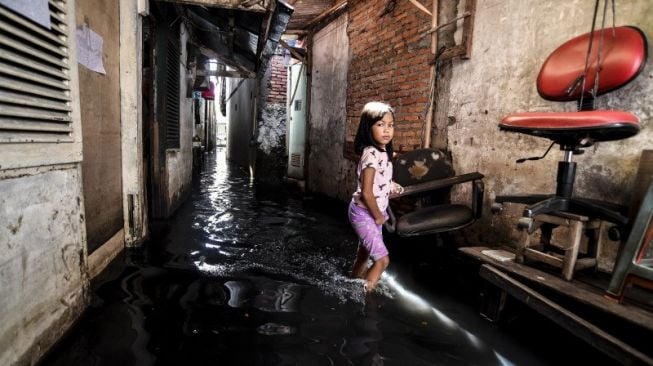 Seorang bocah perempuan berjalan melintasi banjir di kawasan Kedoya Utara, Jakarta Barat, Minggu (21/2/2021). [ANTARA FOTO/Muhammad Adimaja]