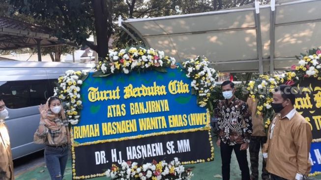 Ketua Umum Partai Era Masyarakat Sejahtera (Emas) Hasnaeni "Wanita Emas" berdiri di samping papan bunga yang ditujukan untuk Gubernur DKI Jakarta Anies Baswedan di Kantor Balai Kota Jakarta Pusat, Minggu (21/2/2021). [Suara.com/Yaumal Asri Adi Hutasuhut]