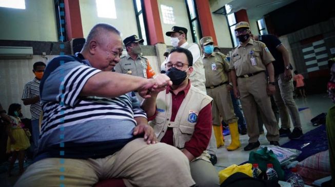 Gubernur DKI Jakarta Anies Baswedan bercengkerama dengan pengungsi banjir di GOR Otista, Jakarta Timur, Sabtu (20/2/2021). [Instagram@aniesbaswedan]