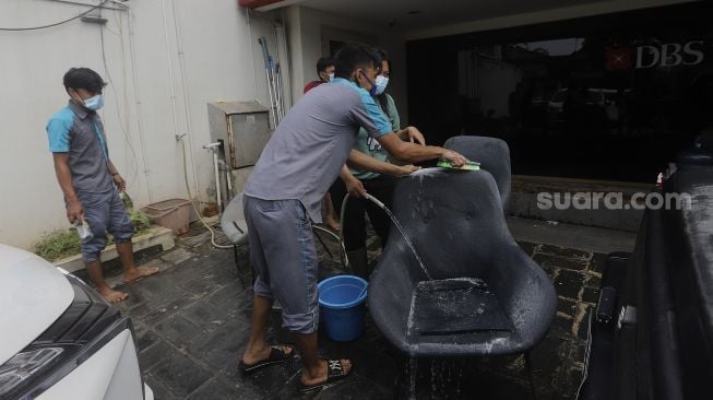 Sejumlah karyawan memberisihkan kursi yang dikeringkan di salah satu bank di kawasan Kemang, Jakarta, Senin (22/2/2021). [Suara.com/Angga Budhiyanto]