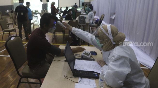 Petugas kesehatan memeriksa kesehatan jurnalis sebelum melakukan vaksinasi COVID-19 di Gedung Penunjang Komisi Pemberantasan Korupsi (KPK), Jakarta, Selasa (23/2/2021). [Suara.com/Angga Budhiyanto]