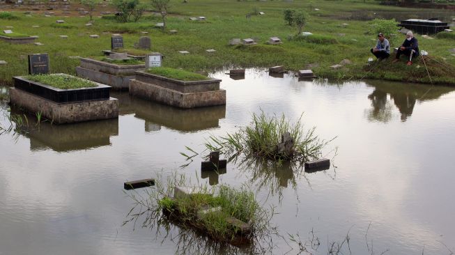 Warga memancing ikan di Tempat Pemakaman Umum (TPU) Tanah Kusir, Kebayoran Lama, Jakarta, Senin (22/2/2021).  ANTARA FOTO/Muhammad Iqbal