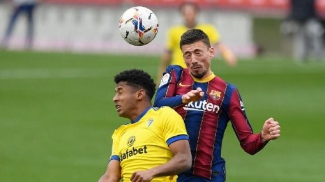 Pemain Barcelona Clement Lenglet berebut bola dengan pemain Cadiz dalam pertandingan Liga Spanyol di Camp Nou, Minggu (21/2/2021). [AFP]