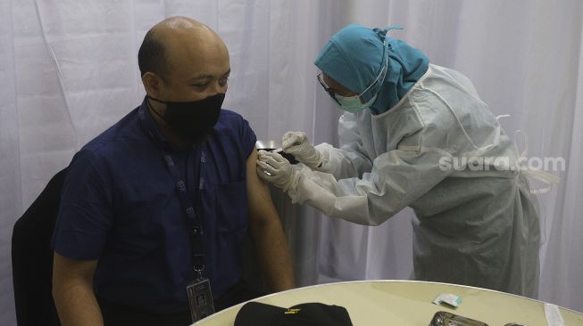 Vaksinator menyuntikkan vaksin COVID-19 kepada penyidik senior KPK Novel Baswedan (kiri) di Gedung Penunjang Komisi Pemberantasan Korupsi (KPK), Jakarta, Selasa (23/2/2021). [Suara.com/Angga Budhiyanto]