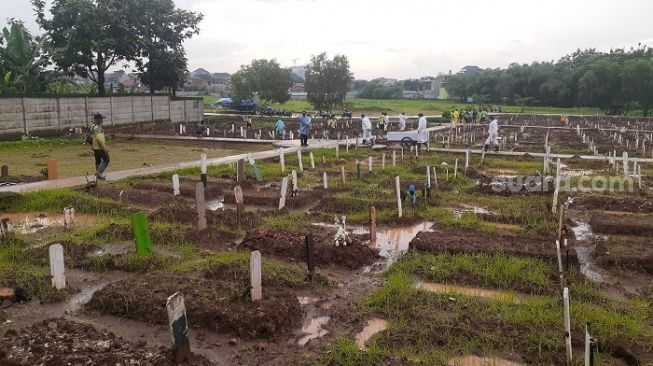 Penampakan para petugas saat hendak memakamkan jenazah Covid-19 di TPU Bambu Apus, Jaktim. (Suara.com/Yaumal)