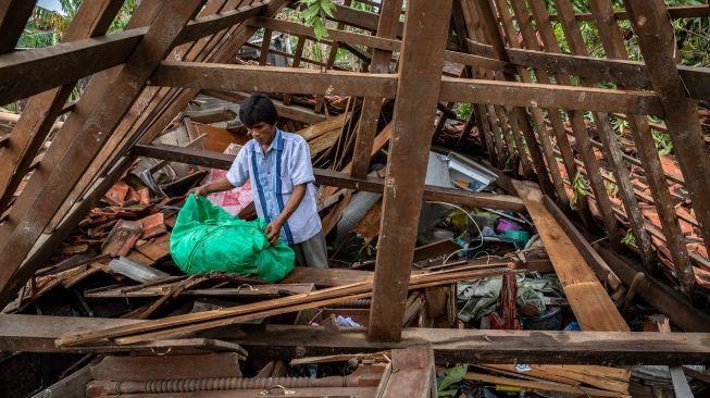 Warga mencari harta benda di dalam rumahnya yang roboh akibat dihantam angin puting beliung di Desa Karangsono, Kecamatan Mranggen, Kabupaten Demak, Jawa Tengah, Rabu (24/2/2021). ANTARA FOTO/Aji Styawan
