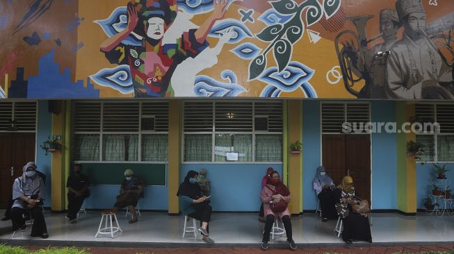 Sejumlah tenaga kependidikan mengantre untuk melakukan vaksinasi COVID-19 di SMA Negeri 70 Jakarta, Rabu (24/2/2021). [Suara.com/Angga Budhiyanto]