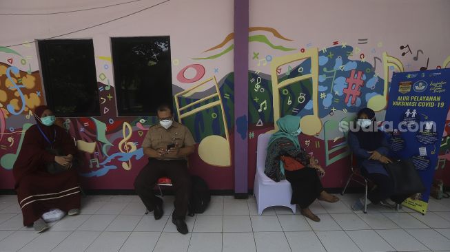 Sejumlah tenaga kependidikan mengantre untuk melakukan vaksinasi COVID-19 di SMA Negeri 70 Jakarta, Rabu (24/2/2021). [Suara.com/Angga Budhiyanto]