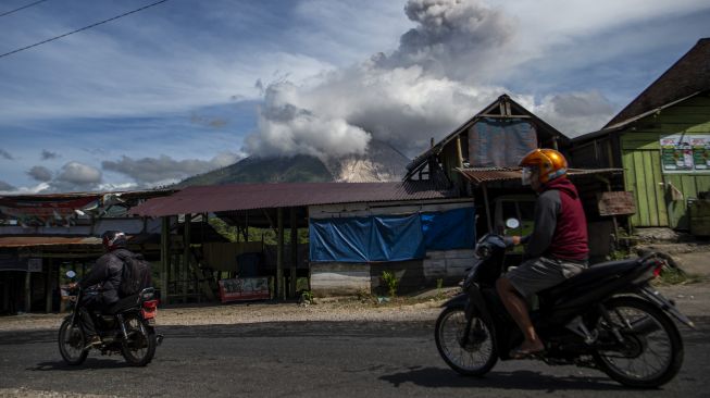 Sejumlah kendaraan melintas dengan latar Gunung Sinabung yang menyemburkan material vulkanik saat erupsi di Desa Tigapancur, Simpang Empat, Karo, Sumatera Utara, Kamis (25/2/2021). ANTARA FOTO/Nova Wahyudi
