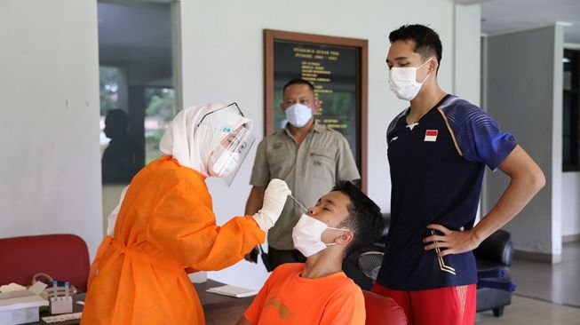 Dua pebulutangkis tunggal putra Indonesia, Anthony Sinisuka Ginting (tengah bawah) dan Jonatan Christie (kanan) mengikuti tes usap PCR di Pelatnas PBSI, Cipayung, Jakarta Timur, Kamis (25/2/2021).