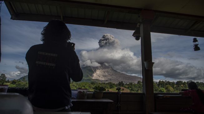 Wartawan mengambil foto Gunung Sinabung yang menyemburkan material vulkanik saat erupsi di Desa Tigapancur, Simpang Empat, Karo, Sumatera Utara, Kamis (25/2/2021). ANTARA FOTO/Nova Wahyudi
