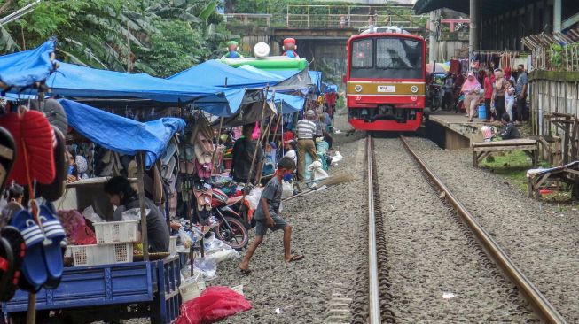 Kereta Commuterline jurusan Jakarta-Stasiun Nambo melintasi pasar kaget pinggir rel di kawasan Citeureup, Kabupaten Bogor, Jawa Barat, Jumat (26/2/2021). ANTARA FOTO/Yulius Satria Wijaya