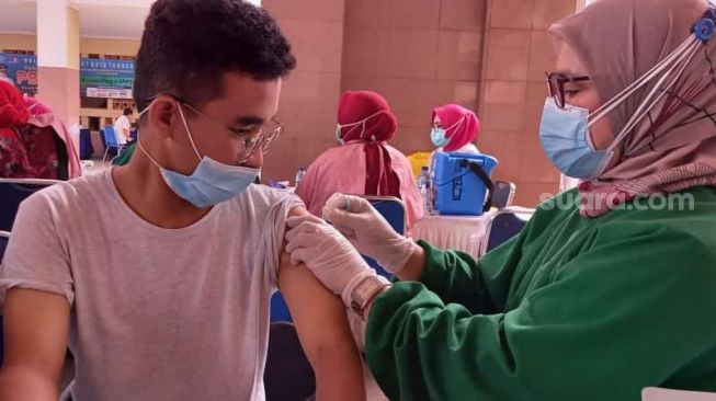 Vaksinator memberikan suntikan vaskin Covid-19 dalam acara vaksinasi massal petugas pelayanan publik, TNI hingga wartawan di Pusat Pemerintahan Kota Tangerang, Jumat (26/2/2021). [Suara.com/Muhammad Jehan Nurhakim]