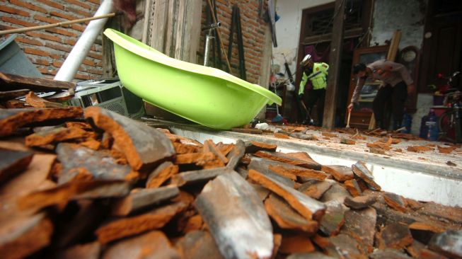 Personel kepolisian membersihkan puing-puing atap rumah yang hancur pasca angin puting beliung di Kelurahan Margadana, Tegal, Jawa Tengah, Jumat (26/2/2021). ANTARA FOTO/Oky Lukmansyah