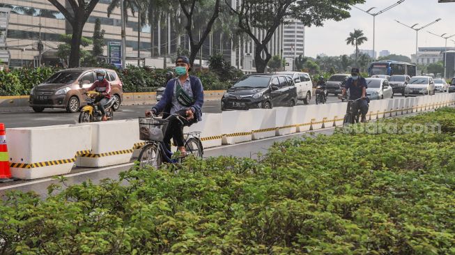 Warga bersepeda dengan menggunakan jalur khusus sepeda di Sudirman, Jakarta Pusat, Jumat (26/2/2021). [Suara.com/Alfian Winanto]