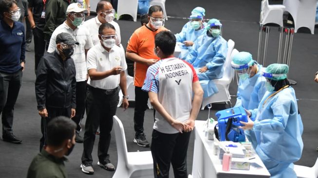 Pebulutangkis Hendra Setiawan berbincang dengan Menpora Zainudin Amali saat menjalani proses vaksinasi Covid-19 untuk atlet di Istora Senayan, Jakarta, Jumat (26/2/2021). (dok Kemenpora)