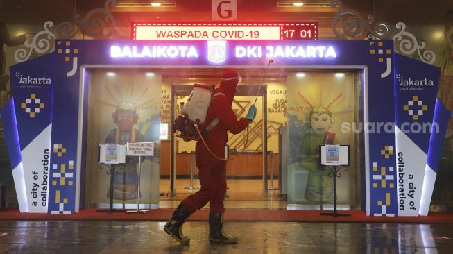 Petugas Dinas Penanggulangan Kebakaran dan Penyelamatan Provinsi DKI Jakarta menyemprotkan cairan disinfektan di lingkungan Balai Kota DKI Jakarta, Selasa (1/12/2020). [Suara.com/Angga Budhiyanto]