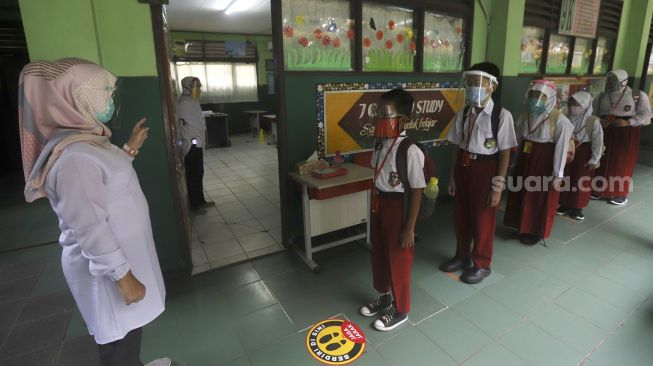 Sejumlah siswa mengantre sebelum memasuki ruang kelas di SDN Pekayon Jaya VI, Kota Bekasi, Jawa Barat, Selasa (4/8/2020). [Suara.com/Angga Budhiyanto]