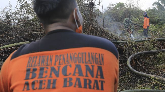 Sejumlah petugas pemadam kebakaran melakukan proses pemadaman lahan gambut yang terbakar di kawasan perbatasan Kabupaten Aceh Barat dan Kabupaten Nagan Raya, Aceh, Minggu (28/2/2021). [ANTARA FOTO/Syifa Yulinnas]