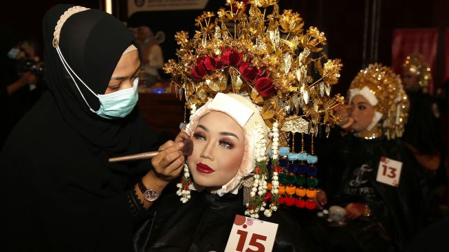 Peserta merias wajah model yang memakai kostum adat pengantin daerah pada rangkaian kegiatan wedding expo, di Banda Aceh, Aceh, Minggu (28/2/2021). [ANTARA FOTO / Irwansyah Putra]