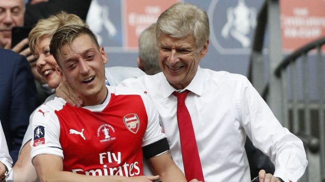 Mesut Ozil (kiri) dan Arsene Wenger saat masih di Arsenal. [ADRIAN DENNIS / AFP]