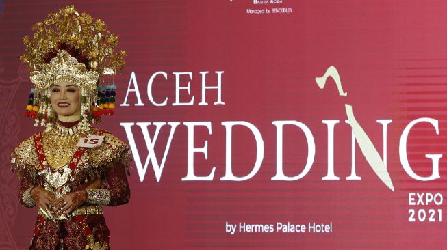 Model memakai kostum adat pengantin daerah yang telah dirias saat lomba marias wajah pada rangkaian wedding expo, di Banda Aceh, Aceh, Minggu (28/2/2021). [ANTARA FOTO / Irwansyah Putra]