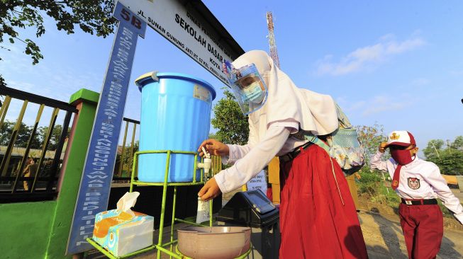 Seorang siswi mencuci tangannya sebelum memasuki gerbang sekolah saat hari pertama dimulainya kembali pembelajaran tatap muka di SDN 212/IV, Kota Jambi, Jambi, Senin (1/3/2021). [ANTARA FOTO/Wahdi Septiawan]