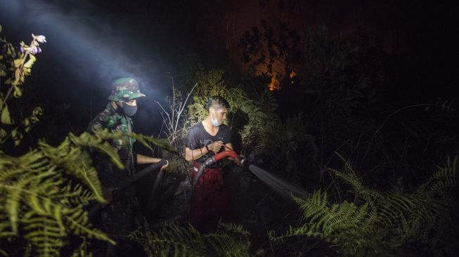 Petugas gabungan dari Satuan Tugas Kebakaran Hutan dan Lahan (Karhutla) Pekanbaru berusaha memadamkan kebakaran di kawasan hutan lindung PT Chevron Pacific Indonesia yang berbatasan dengan lahan masyarakat di Kecamatan Rumbai Pesisir, Kota Pekanbaru, Senin malam (1/3/2021). ANTARA FOTO/FB Anggoro
