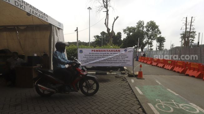 Pengendara sepeda motor keluar dari area pelataran parkir IRTI Monas, Jakarta, Selasa (2/3/2021). [Suara.com/Angga Budhiyanto]