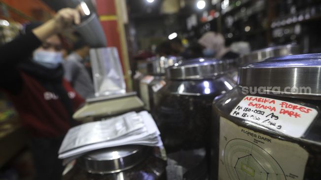 Pekerja menyortir biji kopi di salah satu gerai penjual biji kopi di Pasar Santa, Jakarta, Rabu (3/3/2021). [Suara.com/Angga Budhiyanto]